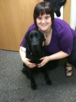 big black lab sitting in front of a crouching me with short hair and a purple shirt